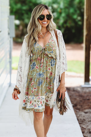 Woman wearing sage floral dress with cream fringe kimono 