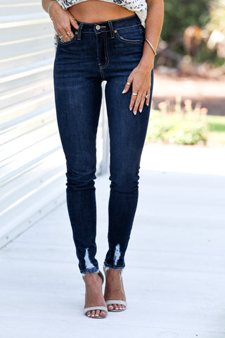 Person wearing dark blue jeans with a blurred outdoor background
