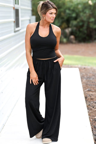 Woman wearing a black outfit standing outdoors on a path.