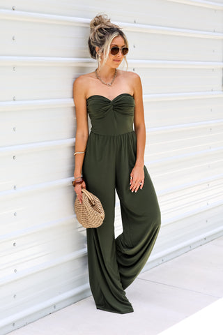 Woman wearing a green jumpsuit against a white wall
