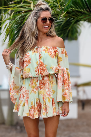 Woman wearing a floral off-shoulder dress with a blurred outdoor background