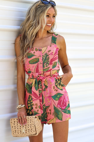 Woman wearing a pink floral dress with a straw bag against a white background