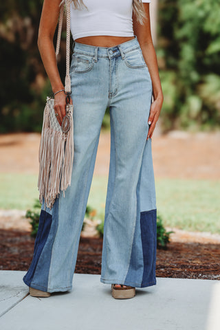 Woman wearing a pair of patchwork jeans and a white crop top 